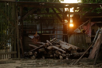 a rooster perched on wood against a sunset light background