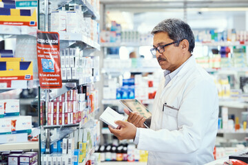 Naklejka na ściany i meble Managing medical matters in his pharmacy. Shot of a mature pharmacist using a digital tablet while working in a chemist.