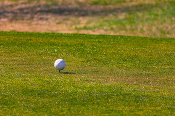 A white golf ball teeing off on a green on a golf course in Germany