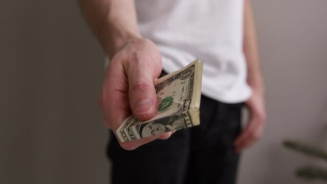 a man takes one dollar out of his pocket and passes it on a gray background