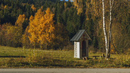 A roadside chapel in the mountains and an autumn landscape