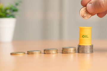 Oil price increase concept: oil barrel over a stack of coins, shallow depth of field