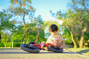 Asian boy about 2 years is riding baby balance bike and fall, learning concept
