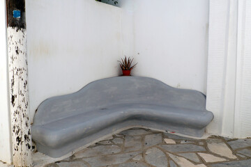 Fototapeta na wymiar As you walk through the streets of Pyrgos, a superb white marble craftsmen's village on the island of Tinos, in the heart of the Aegean Sea, you can rest on this solid stone bench