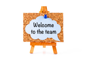 Blue speech bubble with phrase Welcome to the team on a corkboard on a wooden easel.