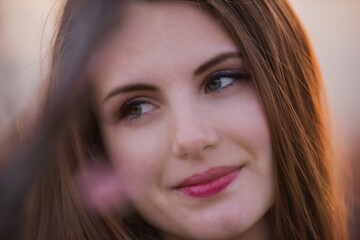 Obraz premium Close-up portrait of Young millennial woman in pink blooming sakura gardens at red sun sunset.