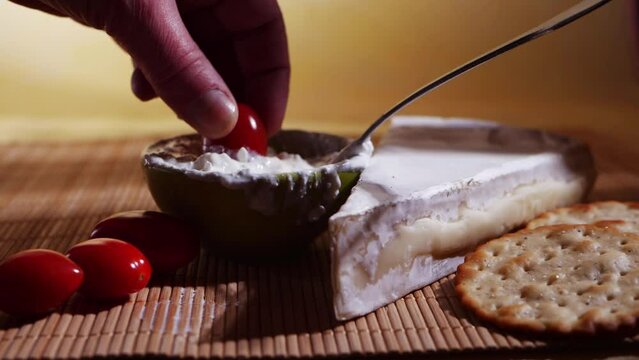 Dipping tomatoes into fresh cheese
