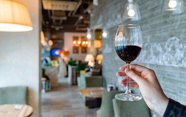 oung girl holding glass goblet with red wine or merlot