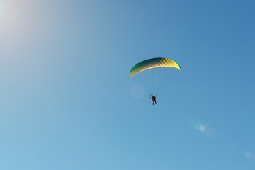 Motorized paraglider flies in the blue sky, extreme sports