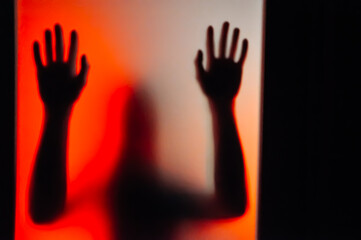 Ghost shadow of hand behind frosted glass, Violence, fear, horror halloween trapped and panic concept, faceless person, Abstract blur hands silhouettes, blurry and soft focus, red, orange and black