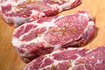 Sliced raw pork meat  with spices on wooden surface, top view
