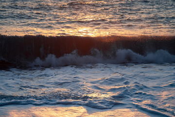 The sea wave. Sunset in the sea. The power of the elements.