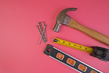 Flatlay of Hammer, Nails, Tape Measure and Level Isolated on a Pink Background