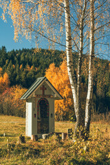A roadside chapel in the mountains and an autumn landscape