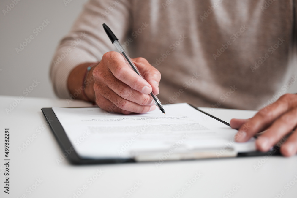 Aufkleber on the dotted line. cropped shot of an unrecognizable businessman filling out a form on a clipboard 