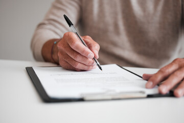 On the dotted line. Cropped shot of an unrecognizable businessman filling out a form on a clipboard...
