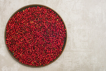 fragrant pink peppercorns in a plate on a gray background. - Powered by Adobe
