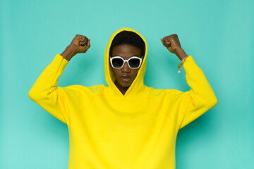 African american woman in yellow hoodie holding fists raised