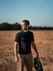 handsome man with short bristles in a black T-shirt in a beveled field
