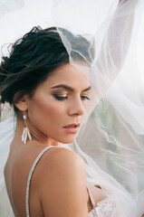 Close-up portrait of a brunette model girl in the role of a bride. Beautiful face, portrait at...