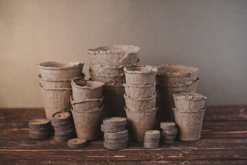 Peat tablets and peat pots for growing seedlings on a wooden background. Eco-friendly.