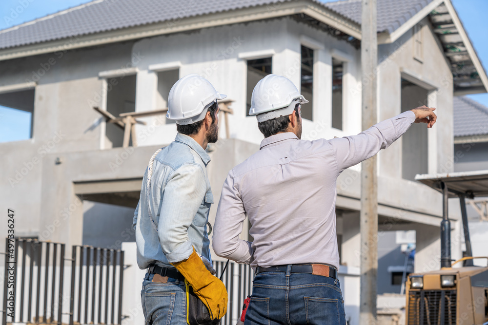 Poster engineer with foreman working on his tablet with blueprints on construction site,meeting,discussing,
