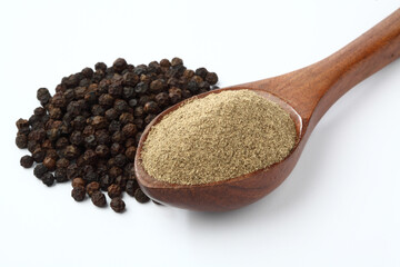 Indian spices Black Pepper powder in a wooden spoon with pepper corns on white background