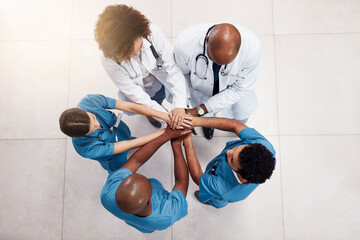 Lets get this day started. High angle shot of a group of young doctors forming a huddle with their...