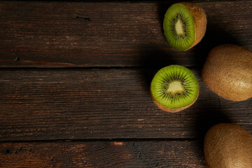 One kiwi fruit cut in halves and two whole kiwi fruit isolated on wooden table and background. Copy...