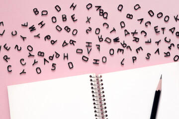 The letters are in disorder, a clean notebook and a pencil for writing. Creative writing concept. Grammar and languages