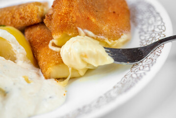 Piece of fried breaded and melted cheese with potato on plate.