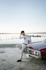 Young black man in nature posing with a convertible. Sunset portrait.