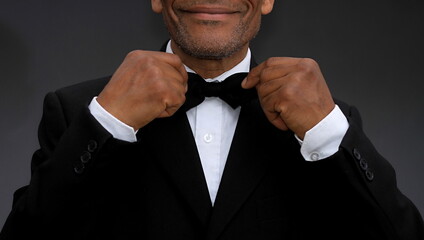 men adjusting his bow tie on grey background with people stock photo 