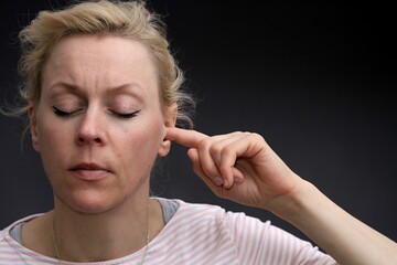 woman suffering from deafness and hearing loss on grey background stock photo