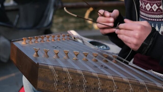 Street musician playing a hammered dulcimer in slow motion in street
