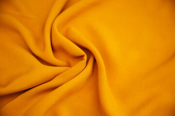 Yellow wrinkled draped fabric. Bright sewing material lies on the table.