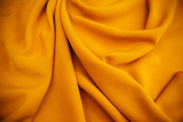 Yellow wrinkled draped fabric. Bright sewing material lies on the table.