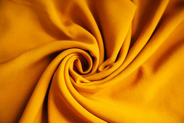 Yellow wrinkled draped fabric. Bright sewing material lies on the table.