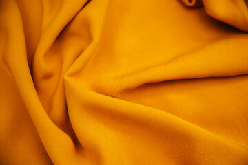 Yellow wrinkled draped fabric. Bright sewing material lies on the table.