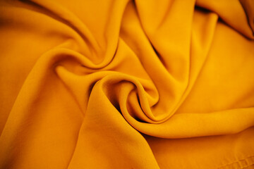 Yellow wrinkled draped fabric. Bright sewing material lies on the table.
