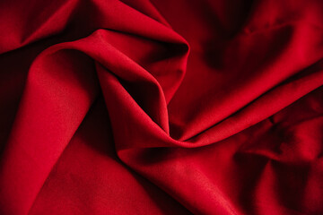 Red wrinkled fabric drapery. Sewing material is on the table.