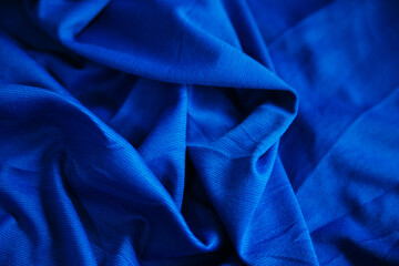 Blue wrinkled draped fabric. Sewing material is on the table.