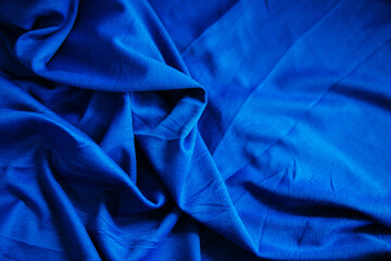 Blue wrinkled draped fabric. Sewing material is on the table.