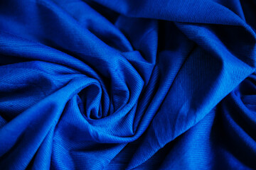 Blue wrinkled draped fabric. Sewing material is on the table.