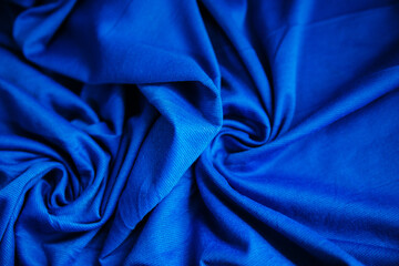 Fototapeta premium Blue wrinkled draped fabric. Sewing material is on the table.