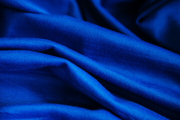Blue wrinkled draped fabric. Sewing material is on the table.