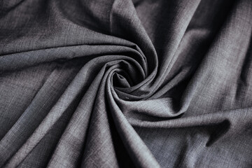 Gray wrinkled draped fabric. Sewing material is on the table.