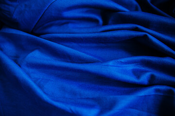 Blue wrinkled draped fabric. Sewing material is on the table.