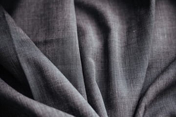 Gray wrinkled draped fabric. Sewing material is on the table.