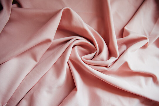 The wrinkled light pink fabric lies in folds and drapery.